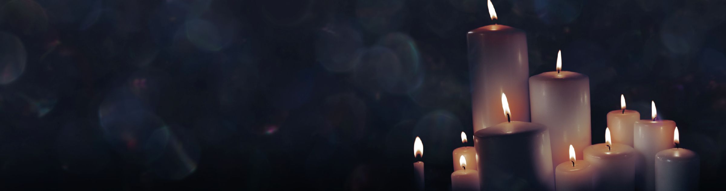 Weiße Kerzen brennen vor einem schwarzen Hintergrund