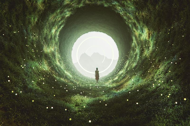 Eine Frau schreitet durch einen grünen Tunnel auf eine helle Öffnung zu