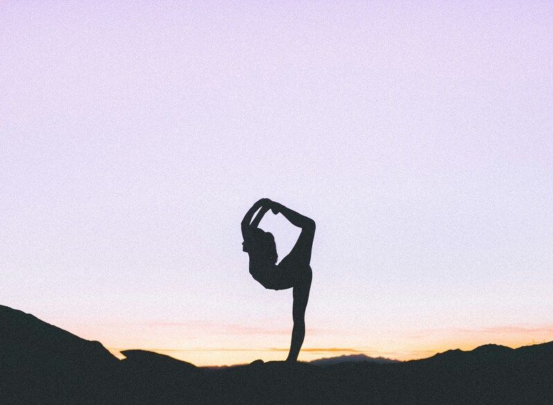 Schatten einer Frau die im Abendlicht eine komplizierte Yoga-Pose macht