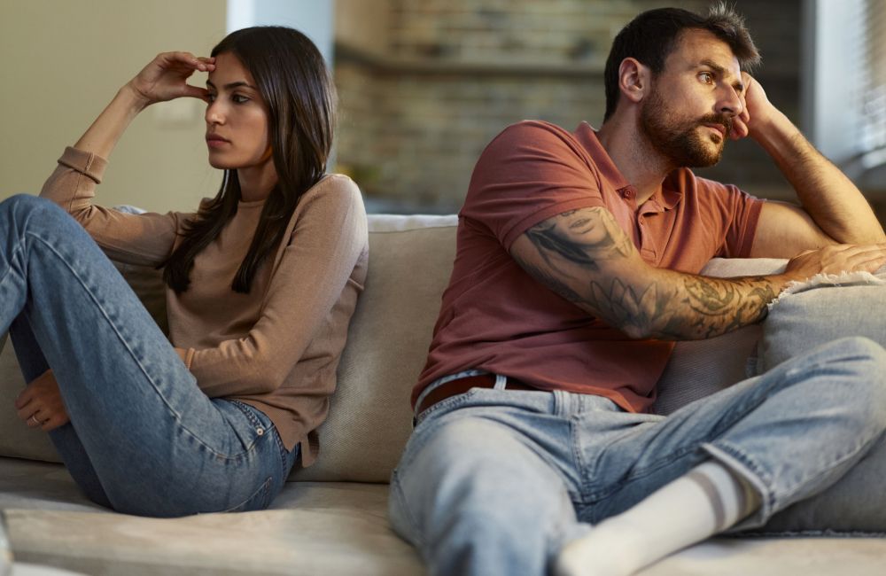 Ein Paar sitzt nach einem Streit traurig auf der Couch