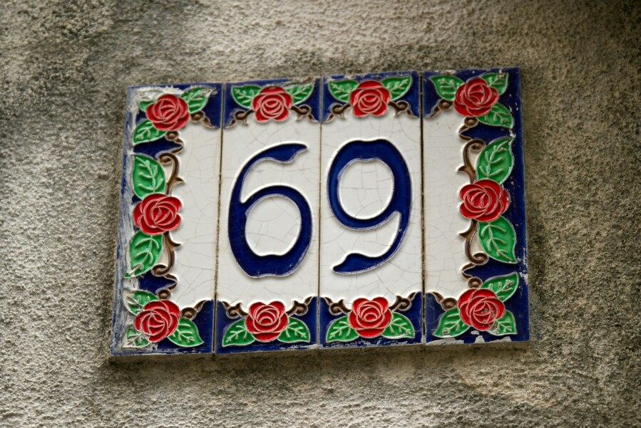 Hausnummernschild in weiß-blau mit der Ziffer 69.