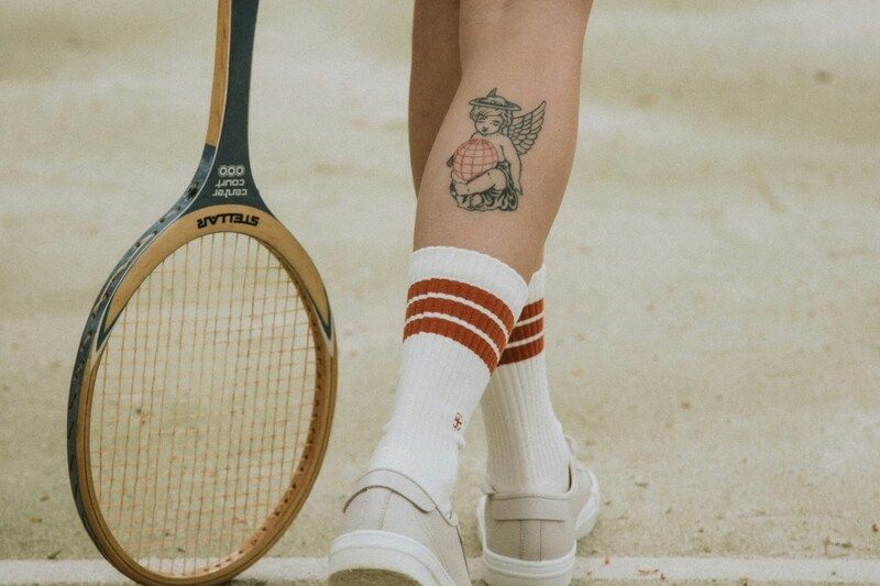 Frau mit Tennisschläger und einem Tattoo auf der rechten Wade