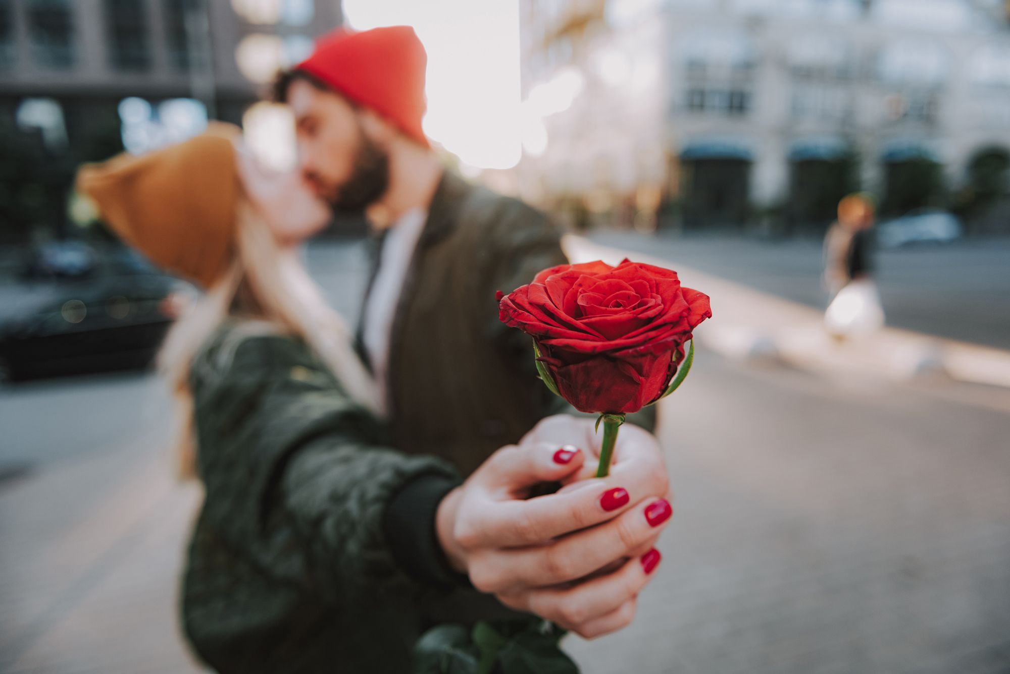 Paar küsst sich und hält eine Rose in die Kamera