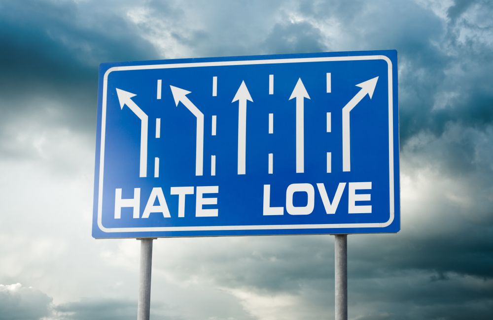 Ein Straßenschild, bei dem die drei linken Pfeile in Richtung "Hate" zeigen und der rechte Pfeil in Richtung "Love".