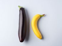 Eine Banane und eine steife Aubergine liegen nebeneinander.