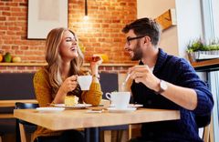 Ein Mann und eine Frau unterhalten sich lachend im Cafe und trinken Kaffee