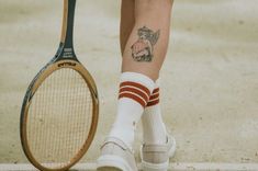 Frau mit Tennisschläger und einem Tattoo auf der rechten Wade