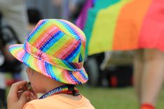 Kind mit Regenbogenhut und Trillerpfeife in der Hand