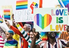 Menschen mit Pride-Flaggen und Schildern, auf denen LGBTQ-Sprüche stehen.